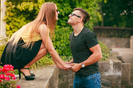 Love and happiness. Dating. Young smilling couple holding hands lovers have fun in park around flovers outside.の写真素材