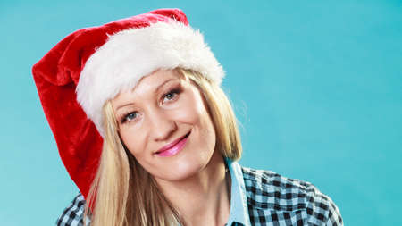 Christmas winter happiness concept. Woman wearing santa helper hat portrait on blueの写真素材