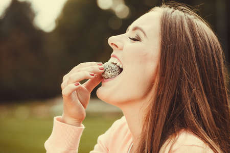 Food and sweets. Appetite and tasty meal dessert. Joyful woman with little cookie cupcake. Happy smiling girl eating small cake outdoor.の写真素材