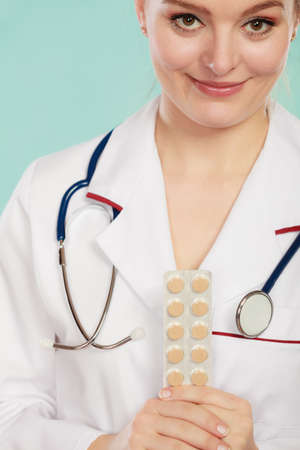 Ways of treatment. Pharmacist doctor in white medical unform apron showing pills. Woman specialist with stethoscope holding medication.の写真素材