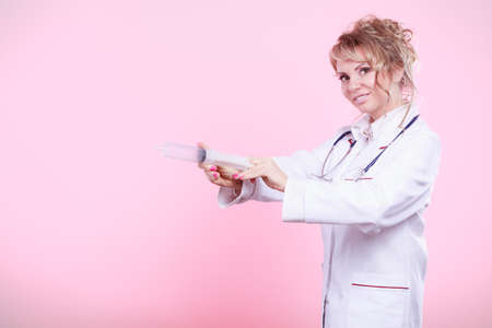 Injection concept. Female doctor with big syringe and stethoscope. Medical help and prevention for disease.の写真素材