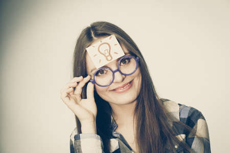 Woman confused thinking seeks a solution, paper card with light idea bulb on her head. Excited girl with many ideas celebrating success. Eureka creativity conceptの写真素材