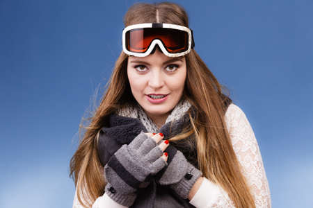Woman skier girl wearing warm clothing ski googles portrait. Winter sport activity. Beautiful sportswoman on blue studio shotの写真素材