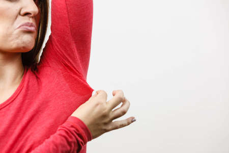 Sweaty girl pointing at wet stain under arm. Bad sweating problem.の写真素材