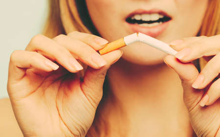 Disappointed pretty girl at breaking up with cigarette. Addicted nicotine problems in young age. Quitting from addiction concept by sorrowful.の写真素材