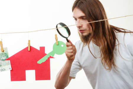 Concept of real estate and deal. Seller man with house model and banknotes. Selling and buying proposition.の写真素材