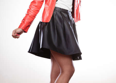 Fashion and style. Part body of mixed race woman wearing stylish red jacket coat and black leather skirt. Fashionable girl posing indoor.の写真素材