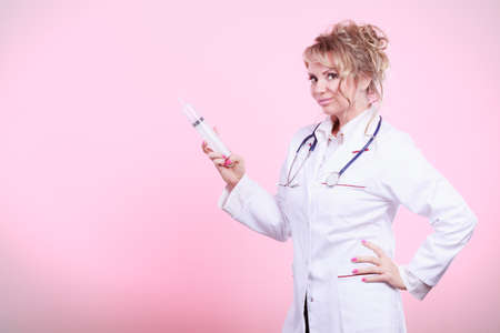 Injection concept. Female doctor with big syringe and stethoscope. Medical help and prevention for disease.の写真素材