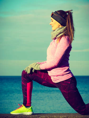 Woman athlete girl training wearing warm sporty clothes outside by seaside in cold weather. Sports and activities in winter or autumn time.の写真素材