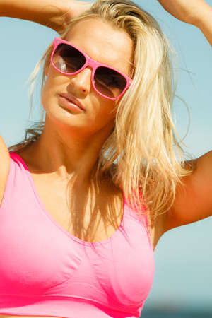 Young blonde pretty girl on beach. Woman wearing sunglasses have active time in summer. Summertime concept.の写真素材