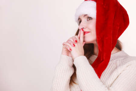 Christmas time. Young lady wearing santa claus hat and warm woolen sweater. Celebration holiday concept.の写真素材