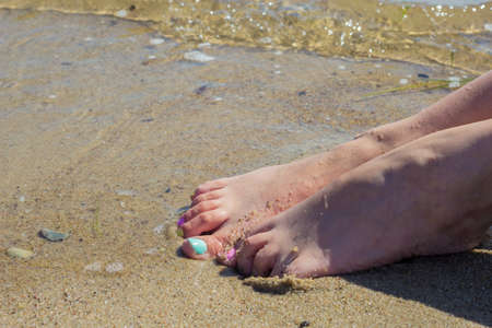 Well cared women feet with colorful nail polish on beachの写真素材