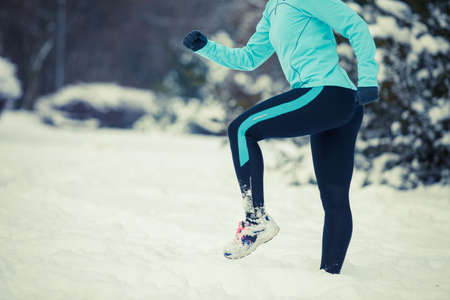 Sport winter people concept. Young lady doing workout in park. Beautiful girl jogging around outside, enjoying wintry time. Woman wearing blue top and leggins.の写真素材