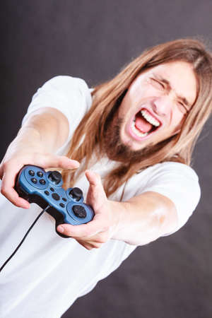 Addiction. Stressed depressed young man playing gaming on pad. Angry guy with controller pad play...