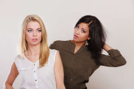 Two young fashionable women caucasian and african posing studio portrait on grayの写真素材