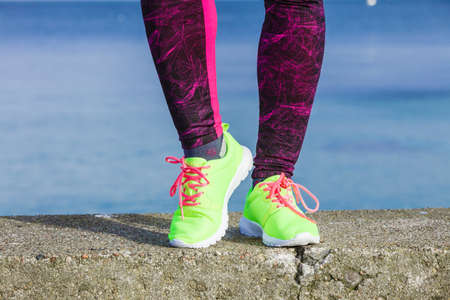 Sports and activities. Part body of training active sporty girl outside. Slim fit legs in vivid color yellow shoes on seaside.の写真素材
