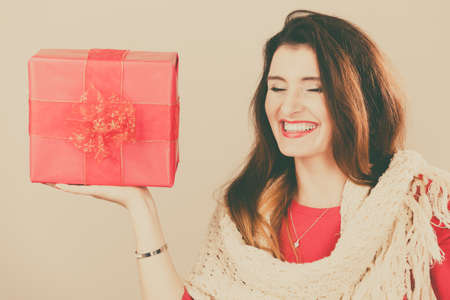Cheerful woman holding present big red gift box. Christmas season celebration concept. Toned imageの写真素材