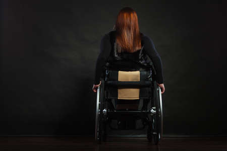 Girl sitting on wheelchair. Back side of disabled woman. Health depression rehabilitation concept.の写真素材