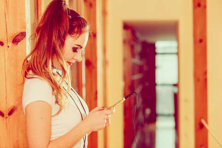 Hobby music technology and free time. Young girl use phone listen music with headphones choose tracks.の写真素材