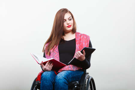 College university and job concept. Mobile technology. Young student worker woman with tablet ebook on wheelchair. Disabled person in real life.の写真素材