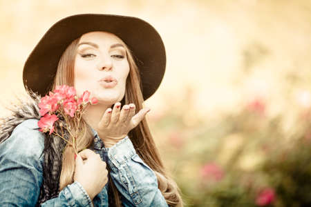 Freedom and leisure. Gorgeous adorable woman holding pink flowers. Romantic portrait of beautiful young lady blowing kiss.の写真素材
