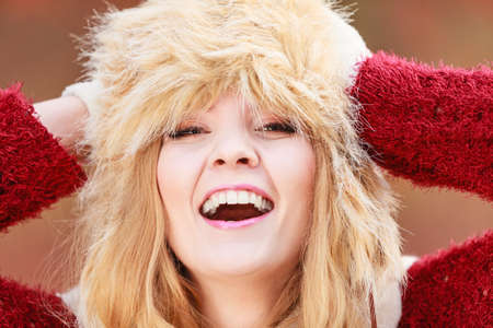 Portrait of pretty fashionable woman in fall forest park. Gorgeous young girl in fur winter hat and sweater pullover. Autumn fashion.の写真素材