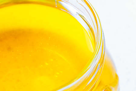full honey pot glass, jar of organic floral honey on table