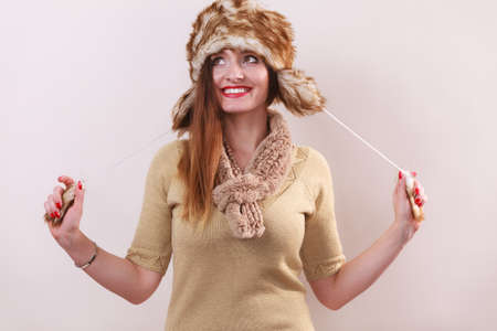 Winter fashion. Young woman wearing fashionable wintertime clothes fur cap woolen sweater studio...
