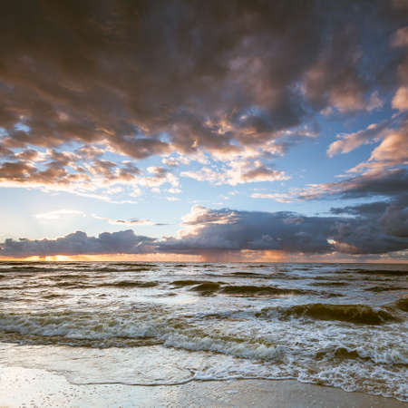 Amazing colorful sunset over evening sea horizon, clouds sky and sandy beach. Tranquil scene. Natural background. Landscape.の写真素材