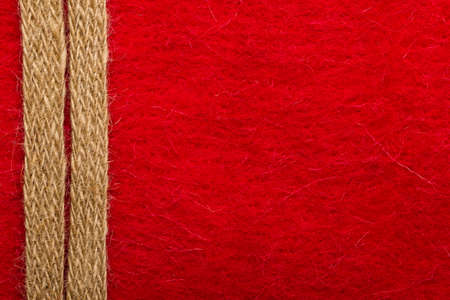 Border or frame formed by rough burlap rope over red textile background.の写真素材