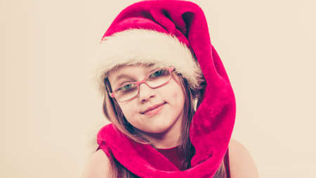 Christmas holiday concept. Toddler girl wearing Santa Claus hat and christmassy dress.の写真素材