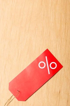 Shopping and sale concept. Red price label with percent sign on wooden surface background. Copyspaceの写真素材