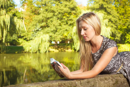 Technology, outdoor relaxation concept. Woman sitting in park, relaxing and using mobile phone, spending her leisure time outsideの写真素材