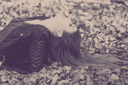 Nature outdoor relax concept. Girl swimming in leaves. Young lady lying in autumnal foliage resting...