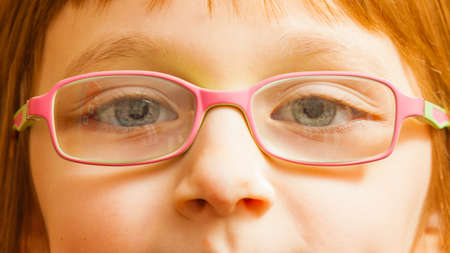 Eyeglasses, vision, eye problems concept. Closeup, face of young toddler girl wearing pink glasses for kids.の写真素材