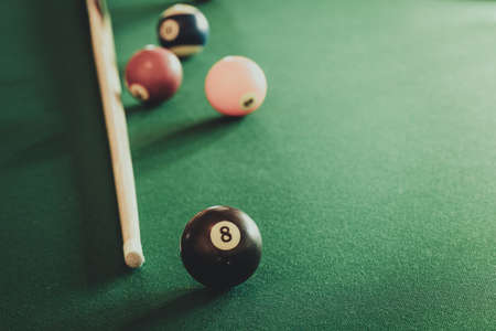 Billiard balls and cue stick on green table. Pool game