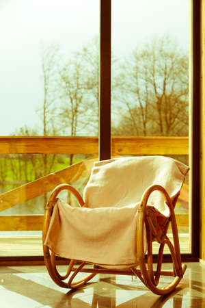 House furniture. Comfortable armchair with blanket on it in daylight with window in background