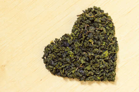 Diet healthcare concept. Green tea heart shaped on wooden surface. Healthy food drink for lower...