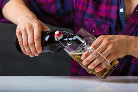 Alcohol liquor drinking relax party concept. Tapster fills stein from bottle. Young male bartender...