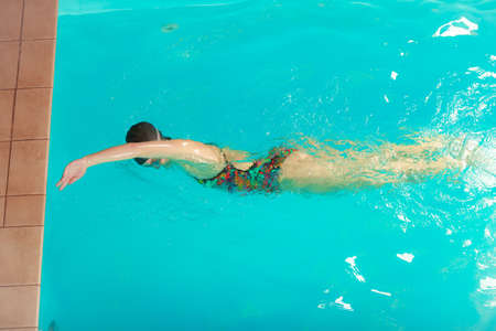 Woman athlete swimming performing crawl style stroke in pool. Active human swimmer taking breath. Water sport comptetition.の写真素材