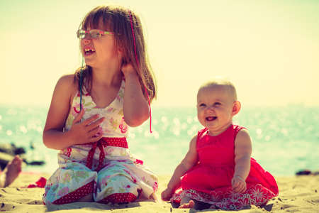 Girl playing and spending time with sister on beach near to sea.の写真素材
