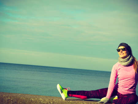 Woman athlete girl training wearing warm sporty clothes outside by seaside in cold weather. Sports and activities in winter or autumn time.の写真素材