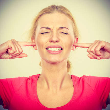 Gestures concept. Blonde woman closing ears with fingers because of big noise, eyes closed, too loud.の写真素材