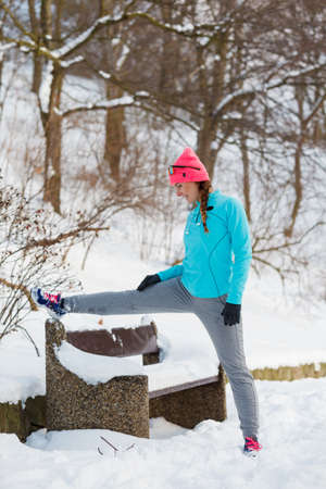 Exercises in winter aura, girl doing streches in winter park. Fitness health fashion conceptの写真素材