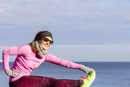 Woman athlete girl training wearing warm sporty clothes outside by seaside in cold weather. Sports...