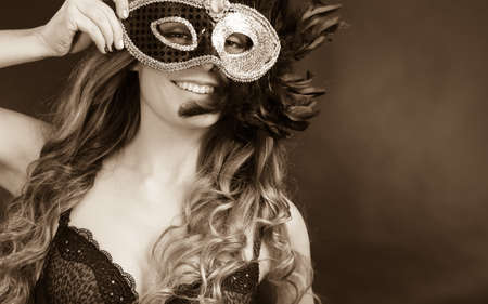 People, fashion, party concept. Sensual woman with carnival mask. Attractive young lady with long brown hair preaparing for celebration.の写真素材