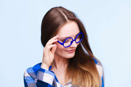 Studying, education and fun concept. Happy smiling nerdy woman in weird big glasses. Studio shot on blue backgroundの写真素材