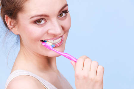 Woman brushing cleaning teeth. Girl with toothbrush. Oral hygiene. Blue background