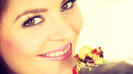 Woman eating oatmeal with nuts and dried fruits for breakfast. Girl holds plastic container take homemade lunch with healthy eating. Dieting nutrition conceptの写真素材