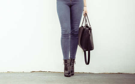 Autumn fashion outfit. Fashionable woman long legs in denim pants black stylish high heels shoes and...